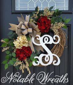 a wreath with the letter s and flowers on it is hanging in front of a door