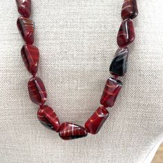 Red, Black and White Hand Knotted Graduated Glass Bead Necklace featuring an unusual necklace comprising 37 unique hand made tetrahedral or humbug shaped parcel graduated glass beads with varying tones of deep red, black and white with varying degrees of visible stripes.  This wonderfully tactile necklace is hand knotted with a deep red cotton thread, it has a screw clasp is 75cm long and weighs 105.2g. This beautiful piece of jewellery began its journey many years ago and may have some very min Red Beaded Agate Necklaces, Unique Red Agate Beaded Necklaces, Handmade Red Agate Necklace, Rectangular Beaded Necklace With Large Beads For Gifts, Handmade Burgundy Beaded Necklaces For Gifts, Handmade Burgundy Beaded Necklaces As Gift, Red Glass Beaded Necklaces With Polished Beads, Unique Red Agate Necklaces, Unique Red Agate Necklace