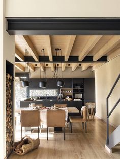 an open kitchen and dining area with wood flooring, black walls and ceiling beams