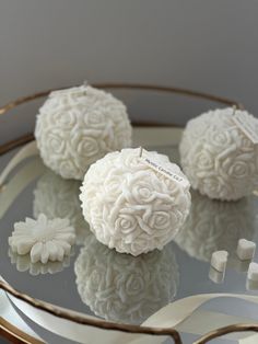 three white flowers sitting on top of a glass table next to marshmallows