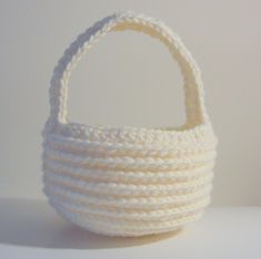 a white crocheted basket sitting on top of a table