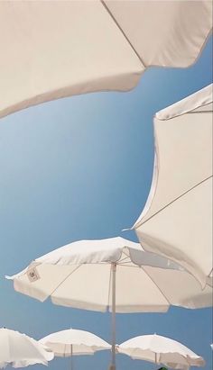 many white umbrellas are lined up against the blue sky