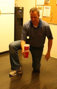 a man holding a red cup on top of a hard wood floor