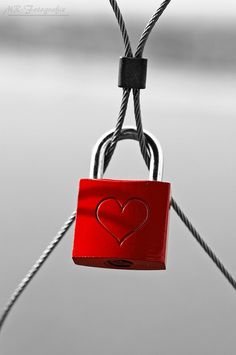 a red padlock attached to a rope with a heart on it's side