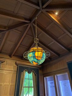 a light fixture hanging from the ceiling in a room with wood paneling and windows