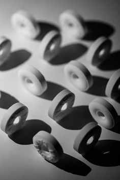 black and white photograph of several different types of donuts on a counter top with shadows from the doughnuts