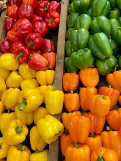 many different types of peppers in wooden boxes