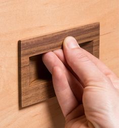 a hand is holding the edge of a wooden object