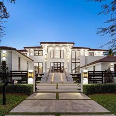 a large white house with lots of windows and lights on it's front entrance