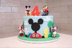 a mickey mouse cake with the number four on it's top and some figurines