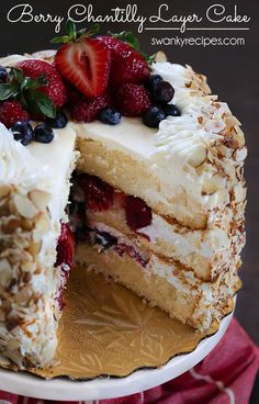 a cake with white frosting and fruit on top is cut in half to show the layers