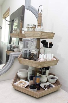 a three tiered wooden tray with various items on it in front of a mirror