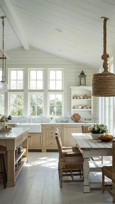 a large kitchen with white walls and wooden flooring, along with an island table surrounded by wicker chairs