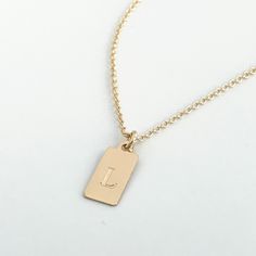 This mini dog tag necklace is perfect for every day wear. This engraved necklace features a small dog tag shaped rectangle in 14k gold fill or sterling silver engraved with a letter of your choice. The font comes in your choice of the classic style (in the photo) or script as shown on the photos. Your new letter or initial necklace will arrive in a complimentary gift box. Please be sure to indicate if you want the script font, otherwise your necklace will be engraved with the classic style. Othe Minimalist Laser Engraved Rectangular Pendant Jewelry, Minimalist Laser Engraved Rectangular Necklace, Classic Gold Rectangular Charm Necklace, Minimalist Rectangular Laser Engraved Necklace, Personalized Gold Dog Tag Charm Necklace, Gold Engraved Rectangular Charm Necklaces, Gold Engraved Rectangular Charm Necklace, Personalized Gold Dog Tag Jewelry, Gold Hand Stamped Dog Tag Jewelry