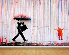 a person with an umbrella walking past a wall covered in colorful paint splatters