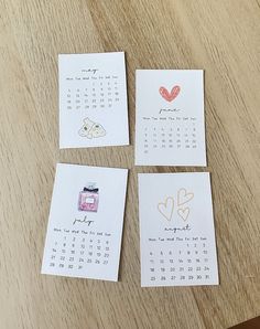 four calendars with hearts on them sitting on top of a wooden table next to each other