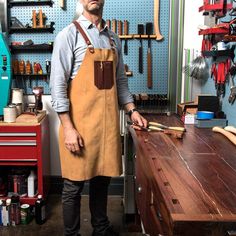 a man wearing an apron standing next to a workbench