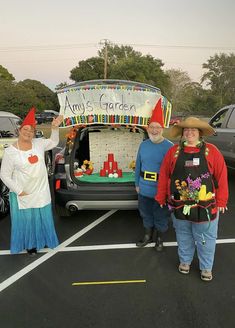 three people in costumes standing next to a car