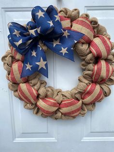 a patriotic wreath with stars and stripes on the front door, hanging from a white door