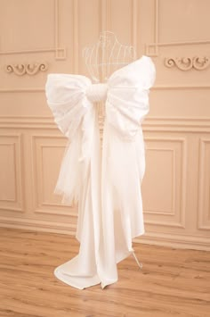 the back of a wedding dress on display in a room with wooden floors and white walls