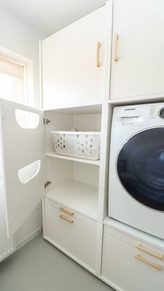 a washer and dryer are in the corner of a room with white cabinets