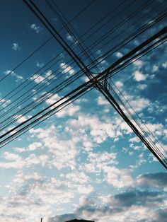 power lines and telephone poles against a blue sky with white clouds in the foreground