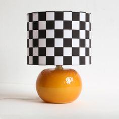 an orange table lamp with a black and white checkerboard lampshade on it