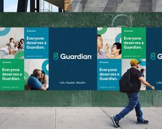 a man walking down the sidewalk past a wall with posters on it