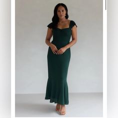 a woman in a green dress posing for the camera with her hands on her hips