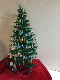 a small green christmas tree sitting on top of a red blanket