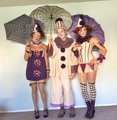 three people dressed in costumes standing next to each other with umbrellas on their heads