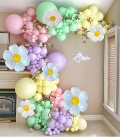 the balloon arch is decorated with pastel colors and flowers for an elegant touch to any room