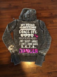 a hoodie with the words dance on it sitting on top of a wooden floor