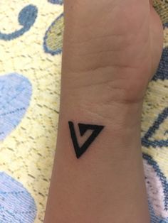 a small black triangle tattoo on the wrist