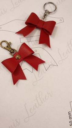 two red bows are attached to each other on a pair of keychains with metal clasps