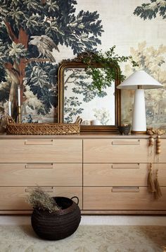 a large mirror sitting on top of a wooden dresser next to a lamp and vase