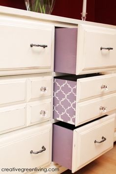 a white dresser with purple drawers and a vase on top