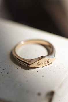 Thin gold signet ring with 'be still' engraving Minimalist Open Signet Ring With Engraving Option, Minimalist Initial Ring With Engraving Option, Minimalist Engraved Ring With Engraving Option, Classic Rose Gold Engraved Ring For Everyday, Classic Engraved Rose Gold Ring For Everyday, Everyday Elegant Personalized Engraved Ring, Elegant Everyday Signet Ring With Engraving Option, 14k Gold Engraved Open Ring For Everyday, Everyday Rose Gold 14k Stamped Signet Ring