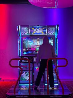 a person standing in front of a slot machine with neon lights on the wall behind them