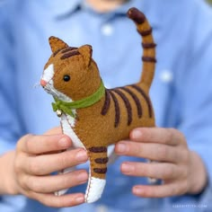 a person holding a small stuffed cat in their hands