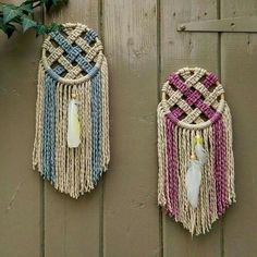 two woven wall hangings on the side of a wooden fence with plants in them