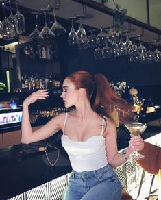 a woman sitting at a bar with a martini in her hand