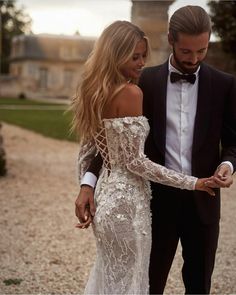 a man in a tuxedo standing next to a woman in a white dress