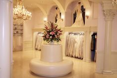 a white wedding cake with flowers on top in front of the bride's dresses