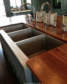 a kitchen counter with two sinks and three faucets