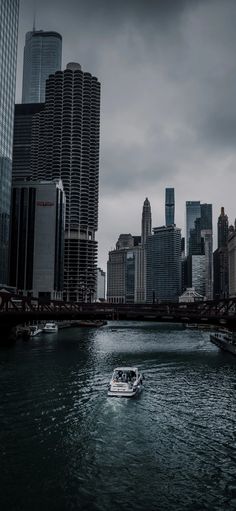 a boat is traveling down the river in front of some tall buildings and a bridge