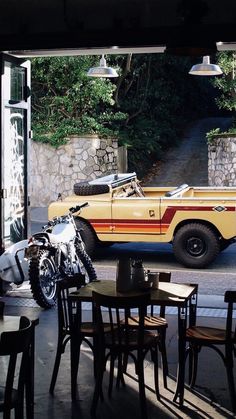 a motorcycle parked next to a yellow car in front of a window with an open door