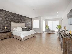 a large bedroom with hardwood floors and white walls, along with an open floor plan