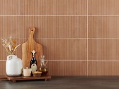 a wooden cutting board sitting on top of a counter next to vases and bottles