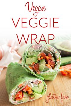 two wraps filled with veggies on top of a wooden cutting board next to sliced vegetables